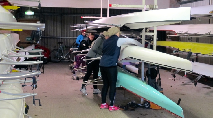A crew of four work together to get a boat out of the Llandaff boat shed.